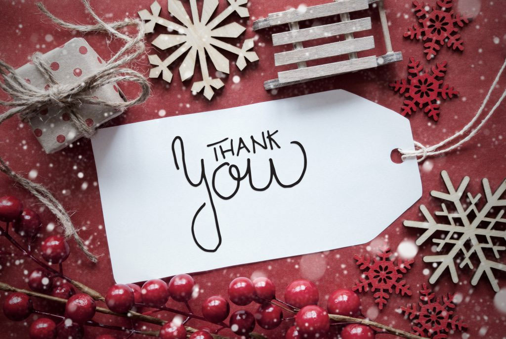 Red Holiday wrapping with a white gift tag with a handwritten "Thank You"